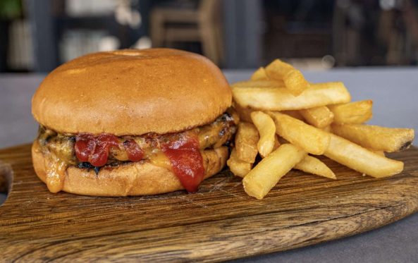 Kids cheeseburger with tomato sauce and a side of fries on a board